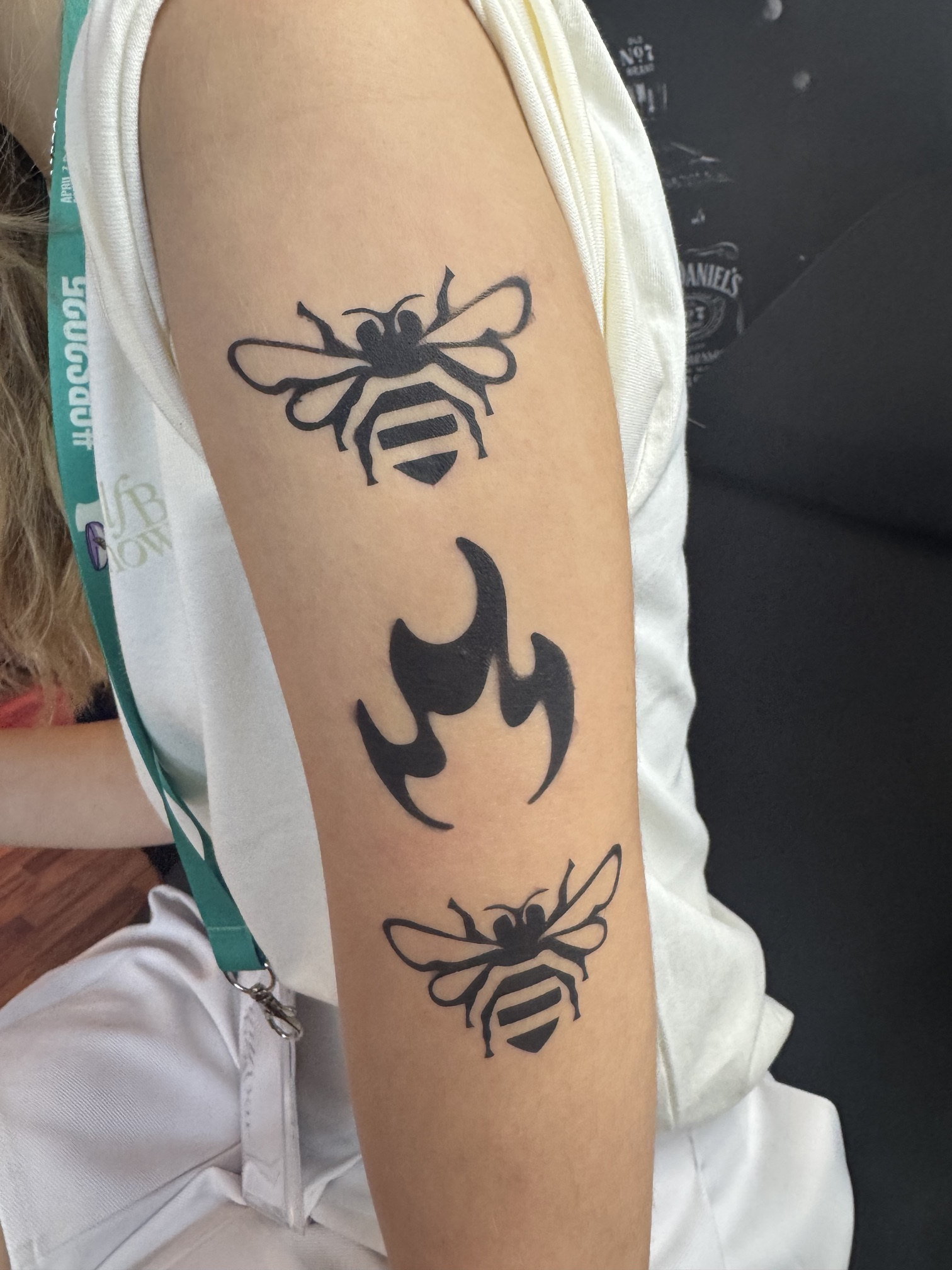 Airbrushed bee and flame tattoos on an upper arm