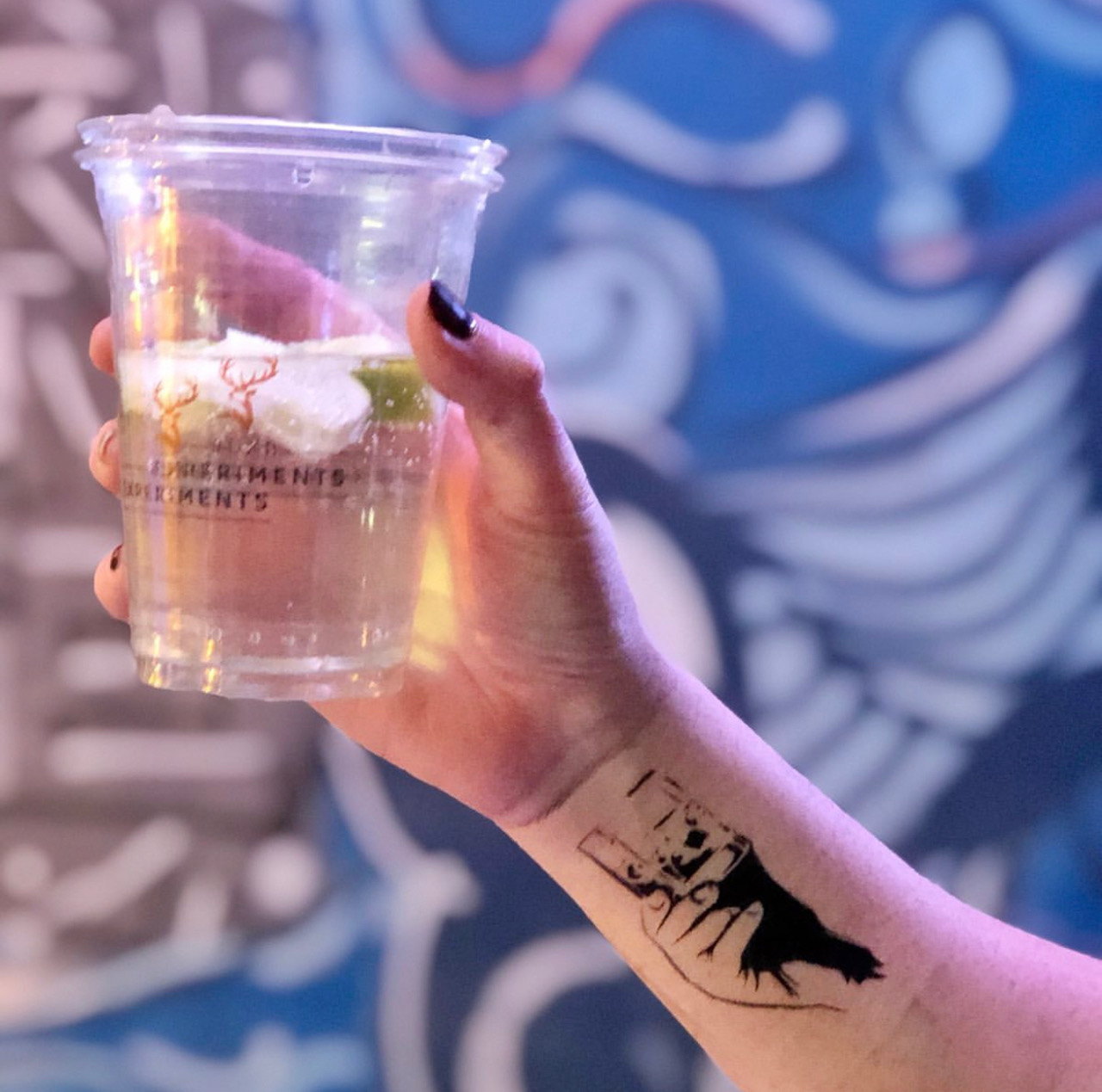 Airbrushed tattoo on a hand holding a drink