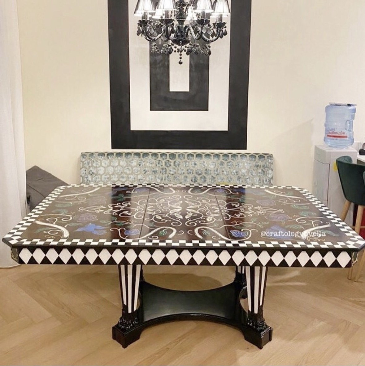 Hand-painted antique dining table under a chandelier