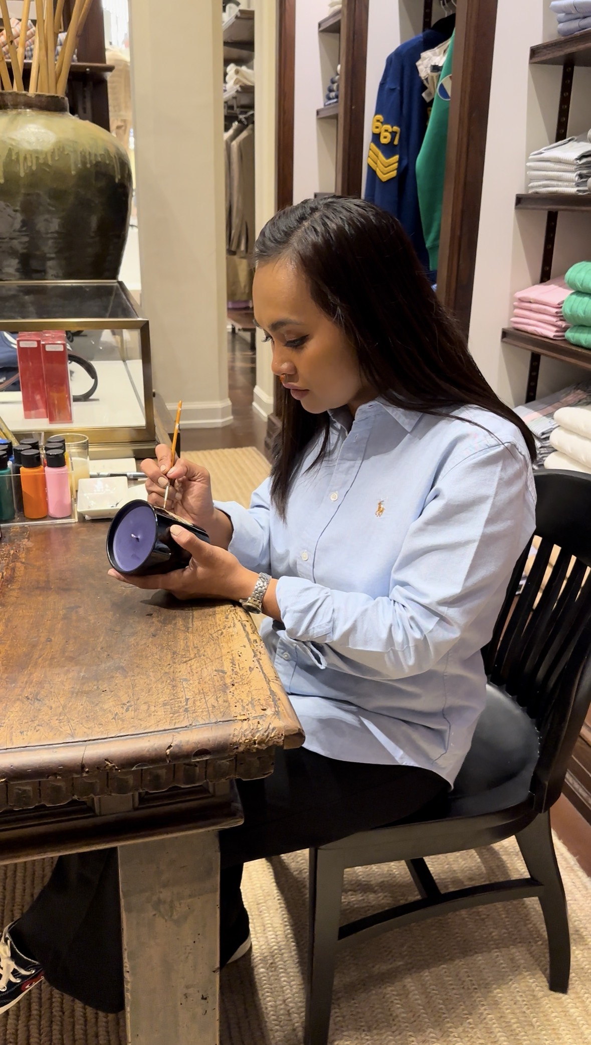 Ella painting a candle jar at the counter