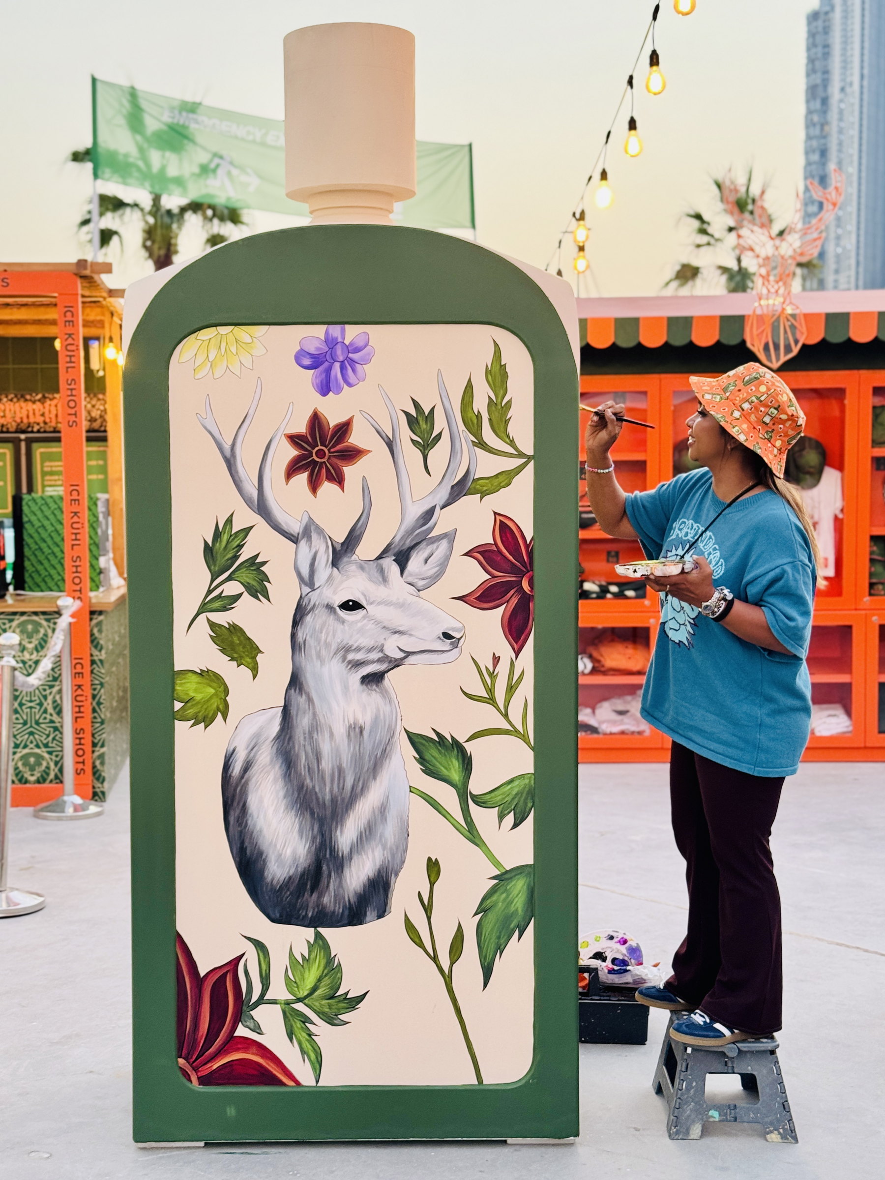 Ella painting a stag on a giant Jägermeister bottle