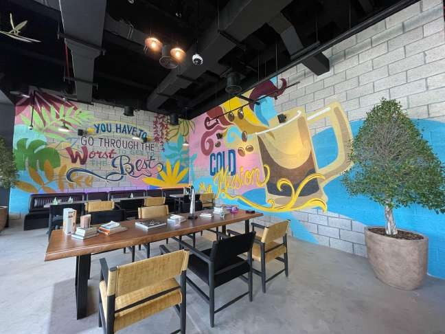 Colourful botanical mural behind the tables at La Vena Cafe
