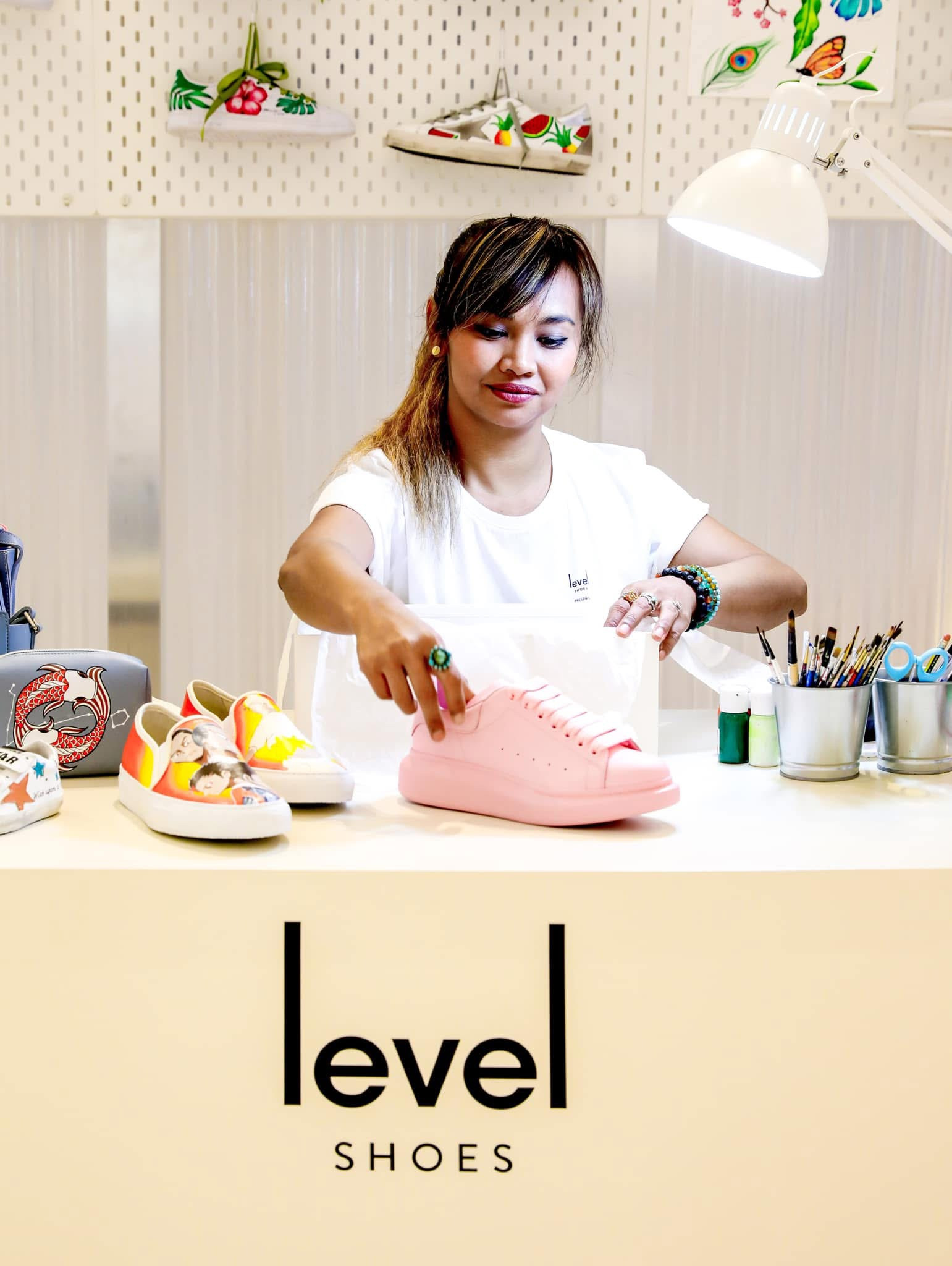 Ella hand-painting a pink sneaker at the Level Shoes counter