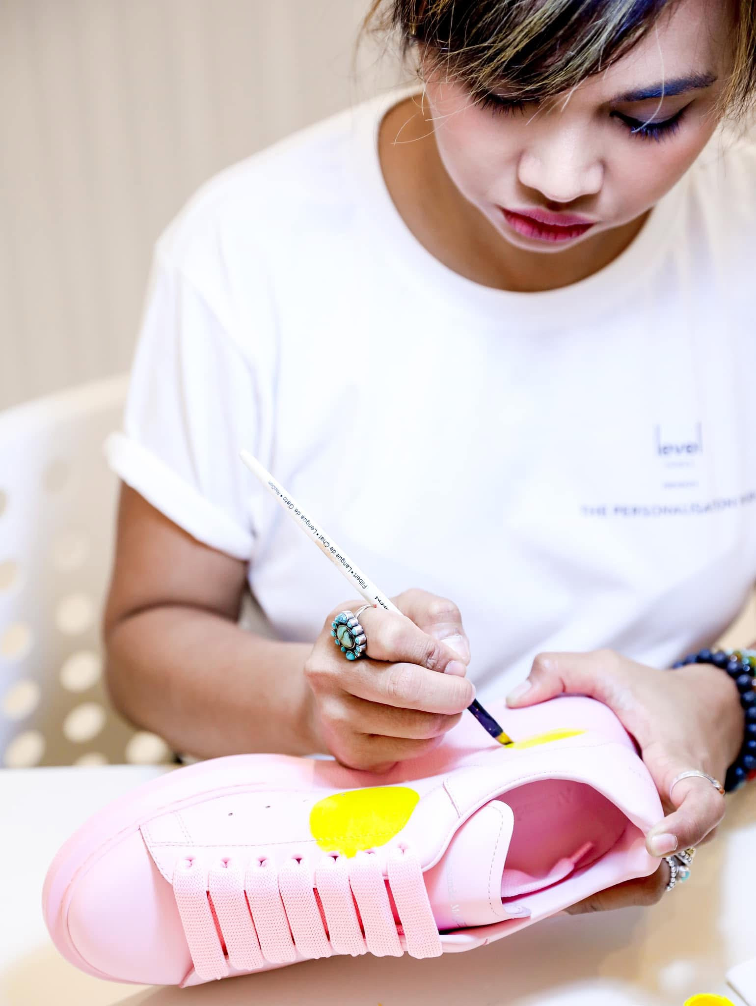 Ella painting a yellow motif onto a pink sneaker