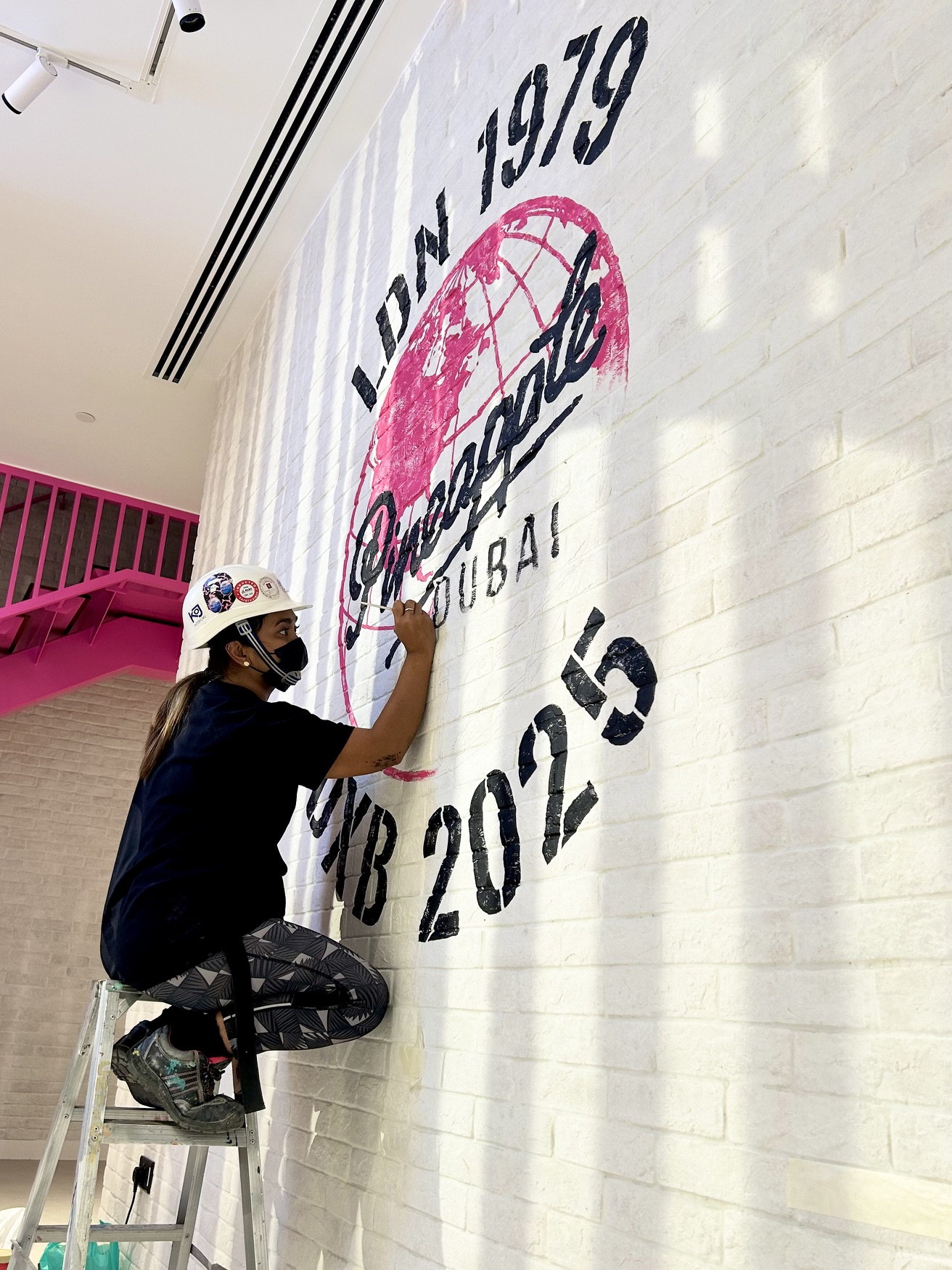 Ella painting the Pineapple crest from a ladder
