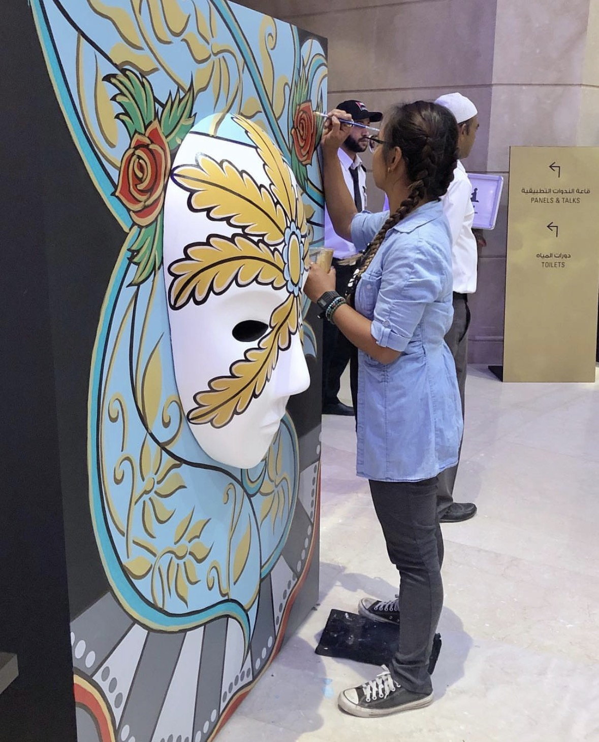 Ella beside a finished mask at the festival